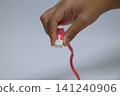 A person's hand plugging in a LAN cable 141240906