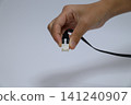 A hand holding a black LAN cable 141240907