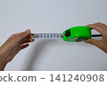 A person's hand measuring length with a tape measure 141240908