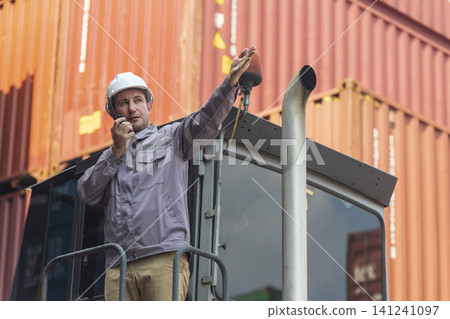 Happy Winner manager, Foreman shipping staff working at Container cargo rising hand and pointing finger for Win in Logistic Business. Leader stand on above container. Happy Winner manager, Foreman shipping staff working at Container cargo rising hand and pointing finger for Win in Logistic Business. Leader stand on above container. 141241097