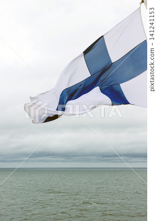 Finnish flag waving in the wind on Baltic Sea on a passenger ferry travelling from Helsinki, Finland. Motion blur. Copy space. Finnish flag waving in the wind on Baltic Sea on a passenger ferry travelling from Helsinki, Finland. Motion blur. Copy space. 141241153