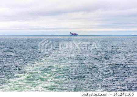 Distant cargo ship sailing across the Baltic Sea between Helsinki, Finland, and Tallinn, Estonia. Minimal maritime seascape with copy space 141241160
