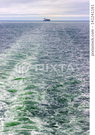 Distant cargo ship sailing across the Baltic Sea between Helsinki, Finland, and Tallinn, Estonia. Minimal maritime seascape with copy space Distant cargo ship sailing across the Baltic Sea between Helsinki, Finland, and Tallinn, Estonia. Minimal maritime seascape with copy space 141241161