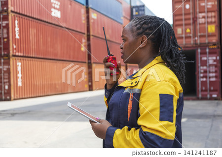Black African woman staff worker check inventory in port cargo shipping yard warehouse. Black African woman staff worker check inventory in port cargo shipping yard warehouse. 141241187