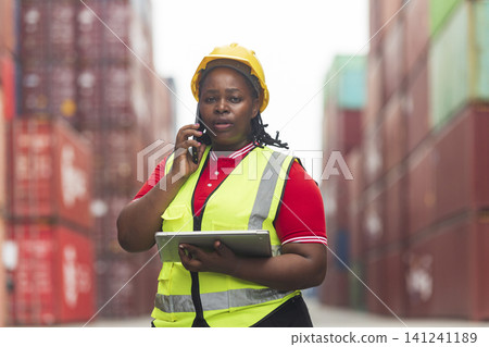 Black African woman staff worker check inventory in port cargo shipping yard warehouse. Black African woman staff worker check inventory in port cargo shipping yard warehouse. 141241189