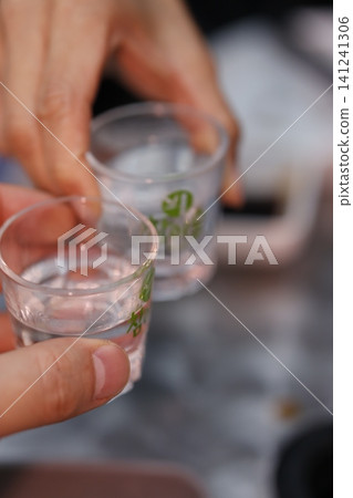 Hands Pouring Water into Glasses Close-Up Hands Pouring Water into Glasses Close-Up 141241306