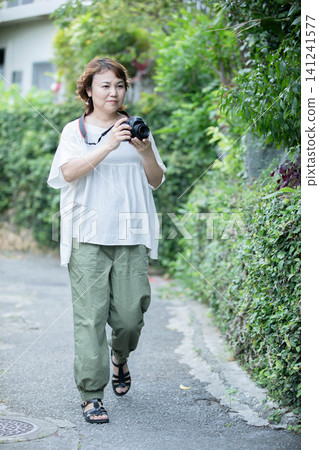 Portrait of a woman strolling around with her hobby SLR camera in hand. Portrait of a woman strolling around with her hobby SLR camera in hand. 141241577