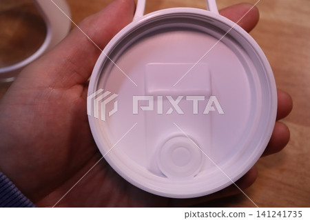 Close-up of White Cup Lid Held in Hand Close-up of White Cup Lid Held in Hand 141241735