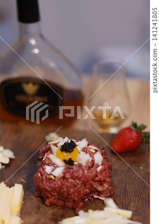 Beef Tartare with Caviar and Egg Yolk on Wooden Board 141241805