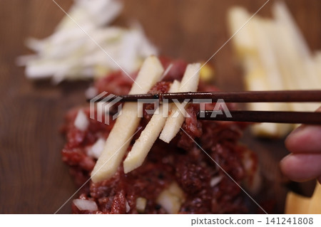 Chopsticks Holding Raw Meat with Apple Slices Chopsticks Holding Raw Meat with Apple Slices 141241808