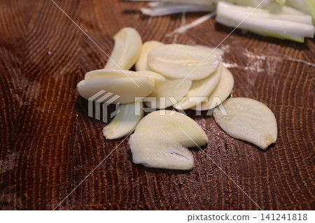 Sliced Garlic and Green Onions on Wooden Cutting Board Sliced Garlic and Green Onions on Wooden Cutting Board 141241818