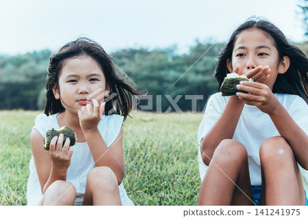 姊妹倆面帶笑容地吃著飯糰 姊妹倆面帶笑容地吃著飯糰 141241975