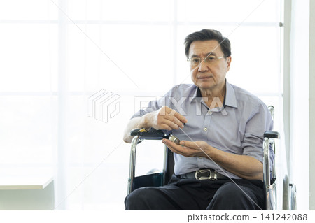 Senior man sitting in wheelchair in hospital and taking pills. Senior man sitting in wheelchair in hospital and taking pills. 141242088