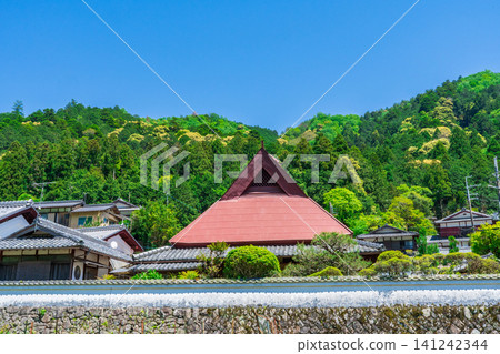 A traditional house with a red corrugated iron roof stands out against the fresh greenery of Yase, Kyoto. A traditional house with a red corrugated iron roof stands out against the fresh greenery of Yase, Kyoto. 141242344