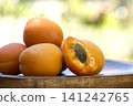 Fresh ripe apricots piled in a wooden bowl with one cut in half showing the pit 141242765