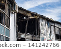 Exterior view of a building heavily damaged by fire, showing charred walls and broken windows 141242766
