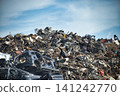 Massive pile of scrap metal and car parts under a cloudy blue sky 141242770