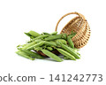 Fresh green peas spilling from a rustic woven basket onto a white background 141242773