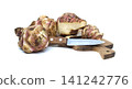 Jerusalem artichokes with a knife on a wooden cutting board against a white background 141242776