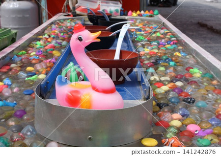 A spinning super ball scooping pool and a pink duck at a festival stall. A spinning super ball scooping pool and a pink duck at a festival stall. 141242876