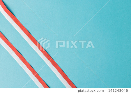 Two parallel diagonal red and white striped ribbons on a clean turquoise background. Excellent minimalist template for Indonesian independence day, cards, announcements, and advertisements. High Two parallel diagonal red and white striped ribbons on a clean turquoise background. Excellent minimalist template for Indonesian independence day, cards, announcements, and advertisements. High 141243046
