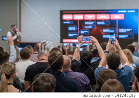 Audience recording business presentation on large screen during conference, people using phones to capture slides Audience recording business presentation on large screen during conference, people using phones to capture slides 141243192