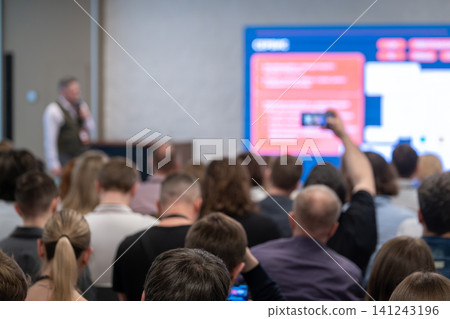 Audience listening to presenter at business conference with attendees recording presentation on phone 141243196
