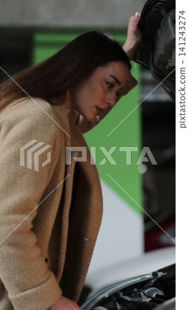 Vertical video Young woman driver near broken car with popped hood having a breakdown problem with her vehicle. Vertical video Young woman driver near broken car with popped hood having a breakdown problem with her vehicle. 141243274