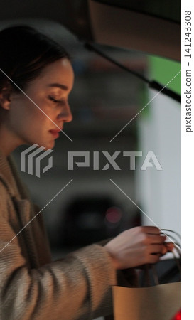 Vertical video Young woman puts paper bags opened car trunk. Shopping, sale, discounts in stores. Vertical video Young woman puts paper bags opened car trunk. Shopping, sale, discounts in stores. 141243308