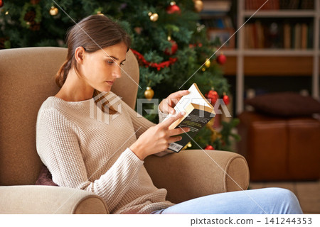 Woman, reading and book on sofa at christmas in home on vacation. Comfortable, female person and fantasy novel for learning or education in living room during festive holiday with decoration 141244353