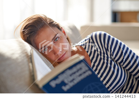 Woman, book and reading with portrait, living room and break or relaxation in house. Student, education and studying for literature, learning and rest at home with novel and couch for knowledge Woman, book and reading with portrait, living room and break or relaxation in house. Student, education and studying for literature, learning and rest at home with novel and couch for knowledge 141244413