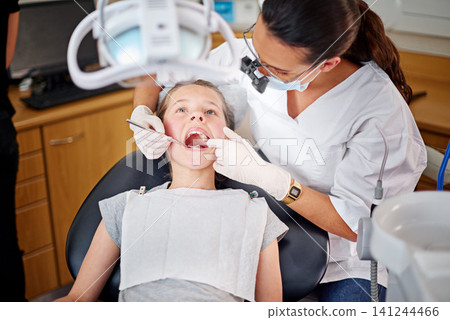 Female dentist, cavity and child for checkup with teeth examination for mouth hygiene with specialist in healthcare. Professional, orthodontist and equipment with oral treatment at clinic for health Female dentist, cavity and child for checkup with teeth examination for mouth hygiene with specialist in healthcare. Professional, orthodontist and equipment with oral treatment at clinic for health 141244466
