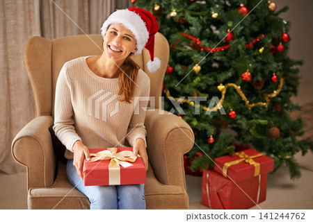 Tree, portrait and woman with gift for Christmas, celebration and religious holiday at home in living room. Female person, lady and smile for xmas present in house, apartment and lounge in Canada Tree, portrait and woman with gift for Christmas, celebration and religious holiday at home in living room. Female person, lady and smile for xmas present in house, apartment and lounge in Canada 141244762