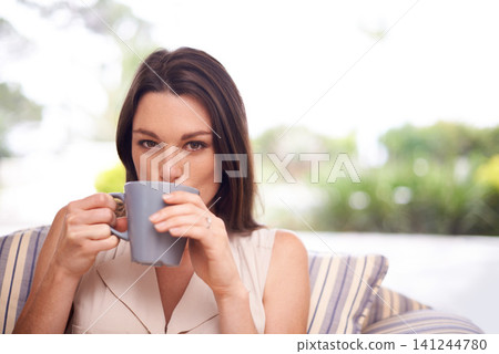 Woman, home and sofa with drinking coffee to relax or chill on break, day off and enjoy. Portrait, female person and happy in living room on couch with cup of tea for peace and calm in lounge. Woman, home and sofa with drinking coffee to relax or chill on break, day off and enjoy. Portrait, female person and happy in living room on couch with cup of tea for peace and calm in lounge. 141244780