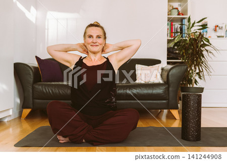 middle-aged woman doing Pilates at home 141244908