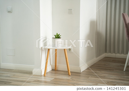 Minimalist workspace with a small table and indoor plant in a home office setting. Modern remote work setup and interior decor Minimalist workspace with a small table and indoor plant in a home office setting. Modern remote work setup and interior decor 141245301