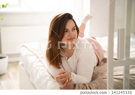 Young woman enjoying a serene morning in bed at home. Self care and mental wellness through home relaxation and morning routine Young woman enjoying a serene morning in bed at home. Self care and mental wellness through home relaxation and morning routine 141245338