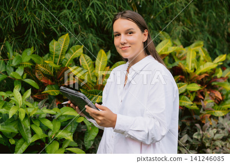 Woman with tablet outdoors surrounded by tropical plants Woman with tablet outdoors surrounded by tropical plants 141246085