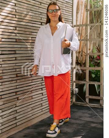 Portrait of woman standing outdoors near modern building Portrait of woman standing outdoors near modern building 141246086