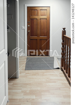 Wooden front door with doormat in home entrance hallway Wooden front door with doormat in home entrance hallway 141246127
