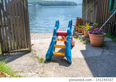 Plastic Children Slide on Lake Shore with Beautiful Nature and Water Background in Austria 141246587
