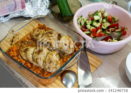 Deliciously Seasoned Baked Chicken Breasts on a Wooden Cutting Board Accompanied by Fresh Vegetable Salad and Condiments in a Kitchen Setting Deliciously Seasoned Baked Chicken Breasts on a Wooden Cutting Board Accompanied by Fresh Vegetable Salad and Condiments in a Kitchen Setting 141246738