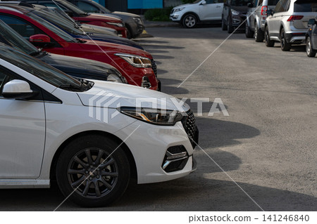 A Lineup of Stylish Vehicles: A Close-Up View of a White Car Parked Among Various Colored Vehicles in a Spacious Parking Lot A Lineup of Stylish Vehicles: A Close-Up View of a White Car Parked Among Various Colored Vehicles in a Spacious Parking Lot 141246840