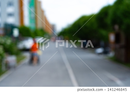 A Blurred Perspective of a Tranquil Urban Street with Lush Greenery and Mild Activity Creating an Ambiance of Relaxation and Everyday Life A Blurred Perspective of a Tranquil Urban Street with Lush Greenery and Mild Activity Creating an Ambiance of Relaxation and Everyday Life 141246845