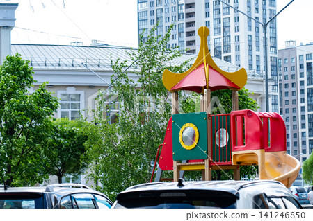 Brightly Colored Playground Equipment Surrounded by Urban Landscape and Vehicles in a Lively Neighborhood Setting Brightly Colored Playground Equipment Surrounded by Urban Landscape and Vehicles in a Lively Neighborhood Setting 141246850