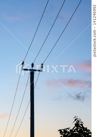 Silhouette of Power Lines Against a Colorful Sunset Sky, Highlighting the Contrast Between Nature and Urban Infrastructure Silhouette of Power Lines Against a Colorful Sunset Sky, Highlighting the Contrast Between Nature and Urban Infrastructure 141246992