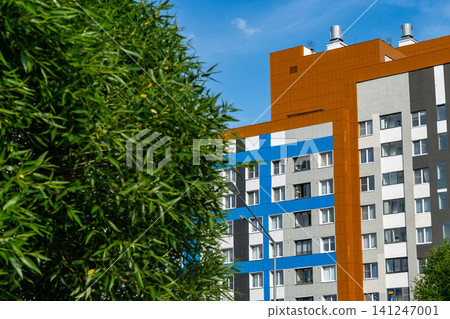 A Vibrant Urban Landscape Featuring Modern Residential Architecture Against a Blue Sky with Lush Greenery in the Foreground A Vibrant Urban Landscape Featuring Modern Residential Architecture Against a Blue Sky with Lush Greenery in the Foreground 141247001