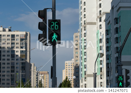 A Vibrant Green Pedestrian Crosswalk Signal Illuminates the Urban Landscape, Encouraging Safe Passage Amongst Modern High-Rise Buildings A Vibrant Green Pedestrian Crosswalk Signal Illuminates the Urban Landscape, Encouraging Safe Passage Amongst Modern High-Rise Buildings 141247071
