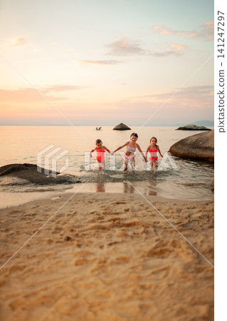 Girls playing at beach running in water during sunset Girls playing at beach running in water during sunset 141247297