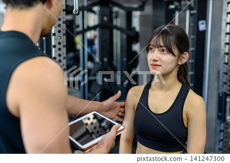 A female fitness enthusiast receives encouragement from her trainer, but the light physical contact raises concerns about sexual harassment. A female fitness enthusiast receives encouragement from her trainer, but the light physical contact raises concerns about sexual harassment. 141247300
